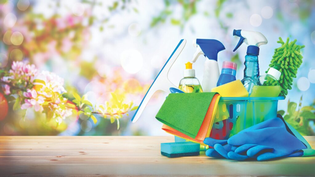basket with cleaning items on blurry spring background